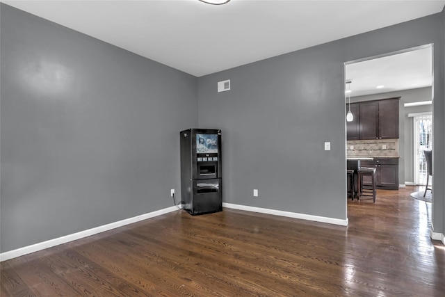 spare room with visible vents, baseboards, and dark wood-type flooring