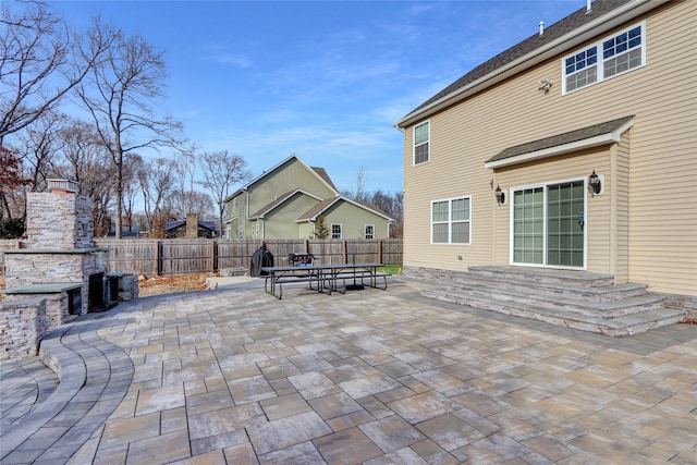 view of patio with a fireplace and fence