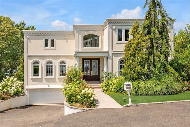 view of front facade featuring an attached garage, stucco siding, aphalt driveway, and french doors