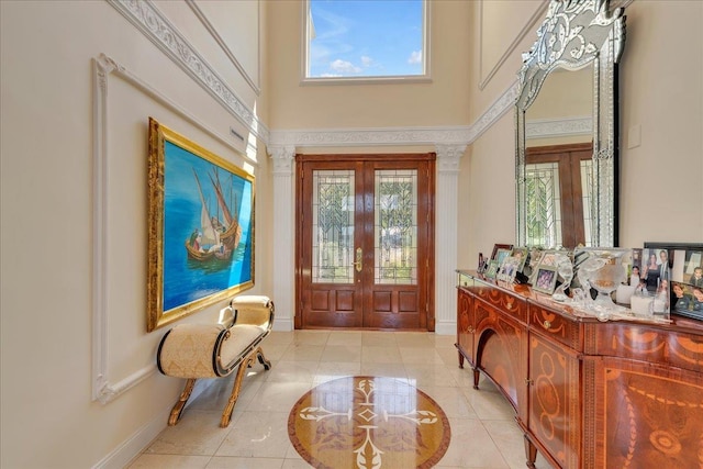 foyer entrance with a healthy amount of sunlight, a high ceiling, light tile patterned flooring, and french doors