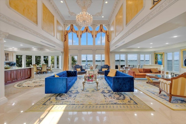 living room with a notable chandelier, a towering ceiling, ornamental molding, light tile patterned flooring, and ornate columns