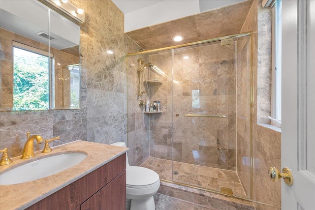 full bathroom featuring visible vents, toilet, vanity, a shower stall, and tile walls