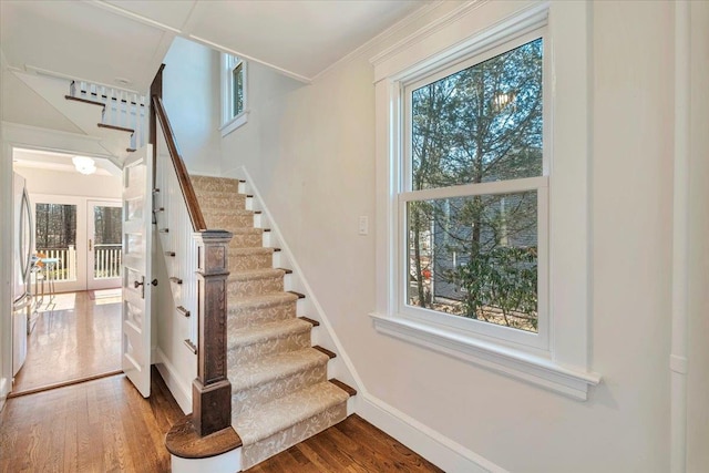 stairs with baseboards, wood finished floors, and crown molding