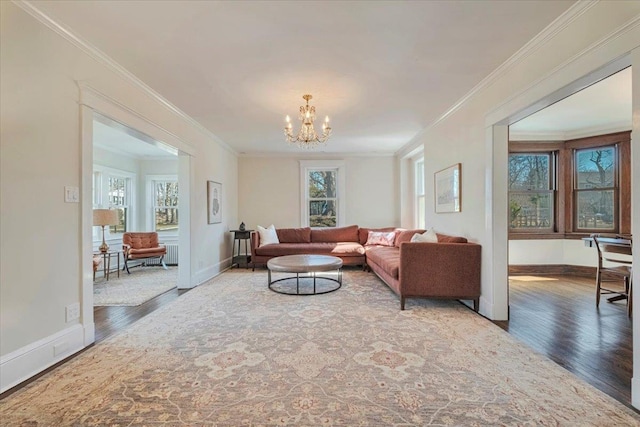 living area with a chandelier, crown molding, baseboards, and wood finished floors