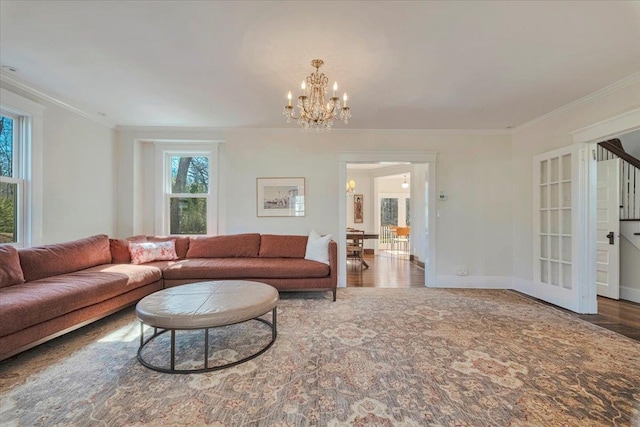 living area with wood finished floors, baseboards, an inviting chandelier, and ornamental molding