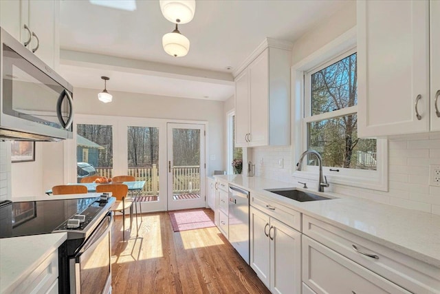 kitchen featuring light wood-style flooring, a sink, white cabinetry, french doors, and appliances with stainless steel finishes