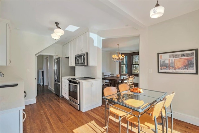 kitchen with light countertops, appliances with stainless steel finishes, a notable chandelier, white cabinets, and dark wood-style flooring