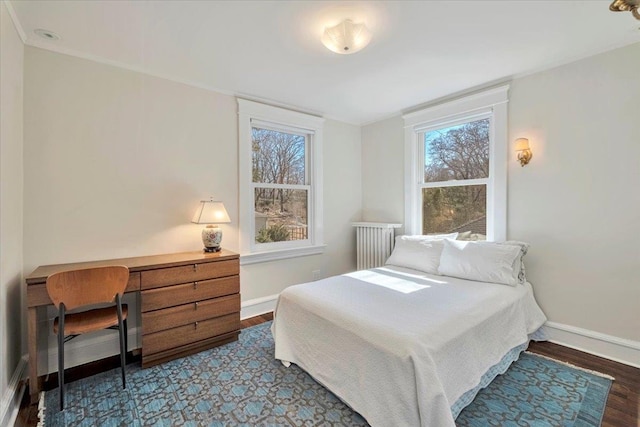 bedroom with radiator, baseboards, and wood finished floors