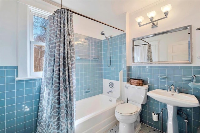 bathroom with toilet, tile walls, shower / tub combo, and a sink