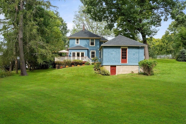 rear view of property featuring a yard, a wooden deck, and a chimney