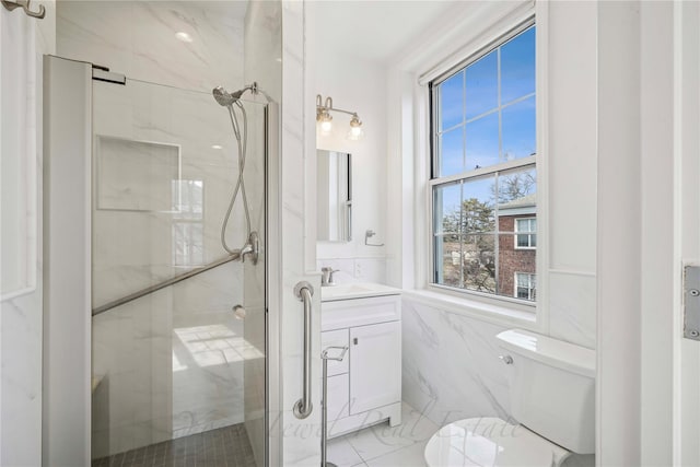 bathroom with toilet, vanity, tile walls, marble finish floor, and a marble finish shower