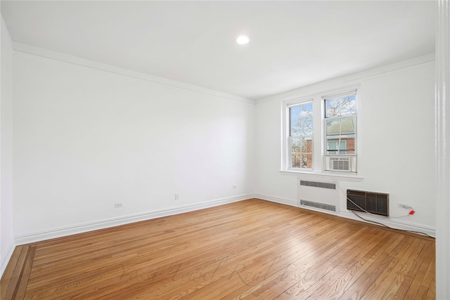 empty room featuring visible vents, radiator, baseboards, ornamental molding, and light wood-style floors