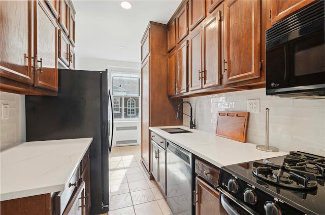 kitchen with black appliances, radiator heating unit, a sink, and decorative backsplash