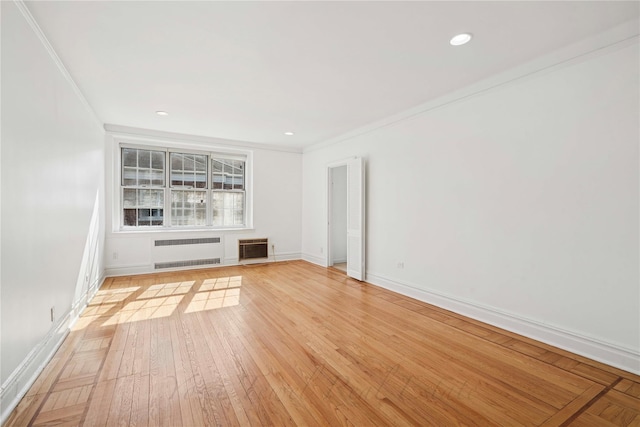 unfurnished living room with baseboards, ornamental molding, light wood-type flooring, heating unit, and radiator heating unit