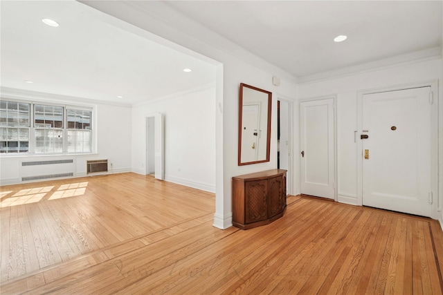 entryway featuring crown molding, light wood finished floors, heating unit, and radiator