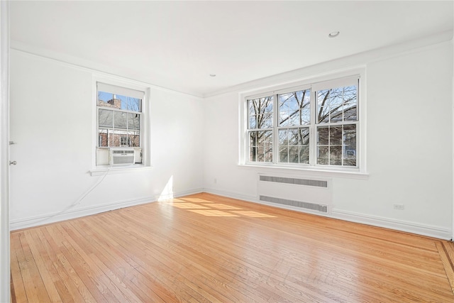 unfurnished room featuring baseboards, wood-type flooring, and radiator