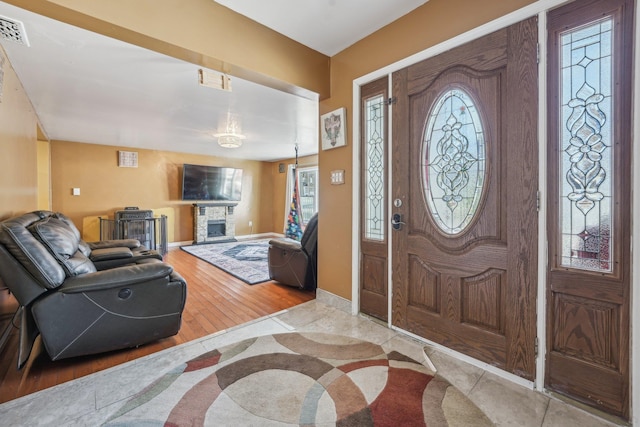 entrance foyer featuring baseboards, a fireplace, visible vents, and wood finished floors