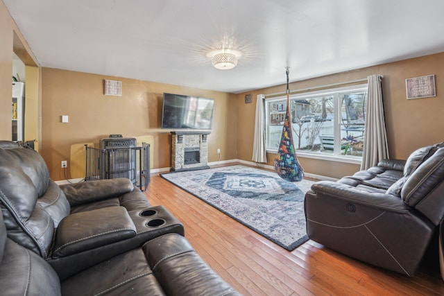 living area with wood-type flooring, a fireplace, and baseboards