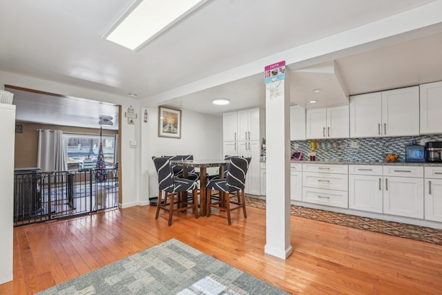 kitchen with baseboards, decorative backsplash, white cabinets, and light wood-style floors