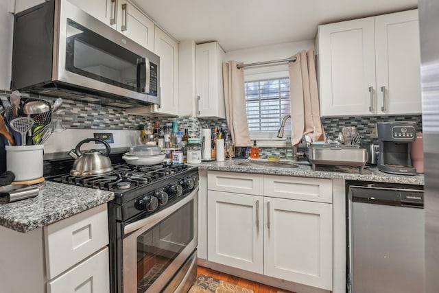 kitchen with tasteful backsplash, appliances with stainless steel finishes, white cabinets, and a sink