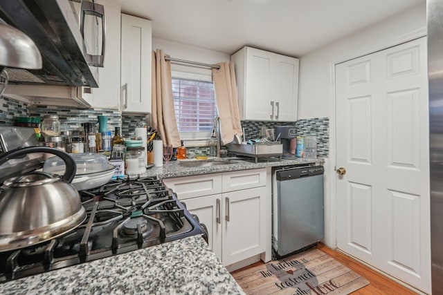 kitchen featuring light wood finished floors, white cabinetry, a sink, gas range, and dishwasher