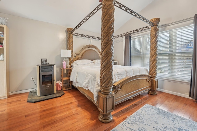 bedroom featuring baseboards, lofted ceiling, wood-type flooring, a wood stove, and heating unit