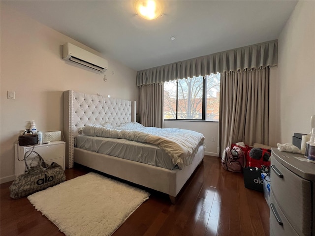 bedroom featuring an AC wall unit, dark wood finished floors, and baseboards