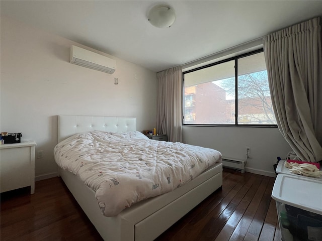 bedroom with a baseboard heating unit, dark wood finished floors, baseboards, and a wall mounted AC