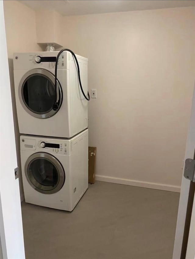 laundry room with laundry area, stacked washer and clothes dryer, and baseboards