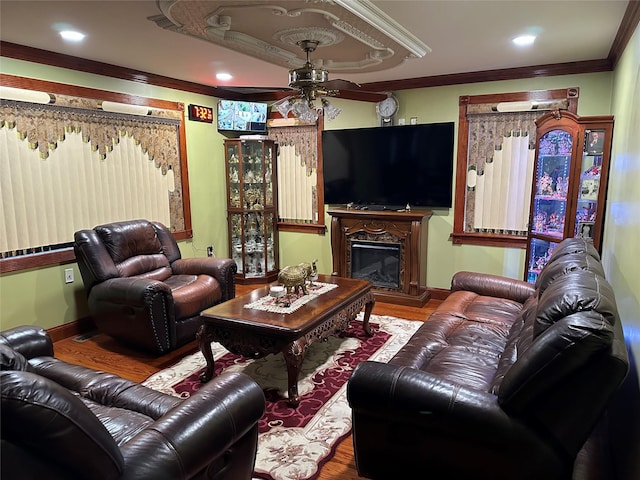 living area featuring a glass covered fireplace, wood finished floors, baseboards, ornamental molding, and a raised ceiling