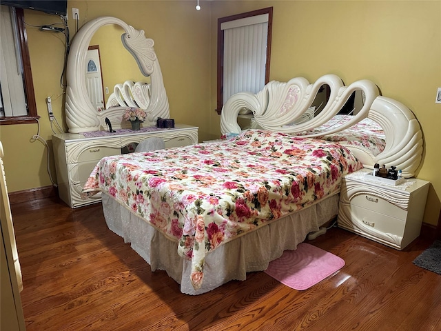 bedroom with dark wood-type flooring and baseboards