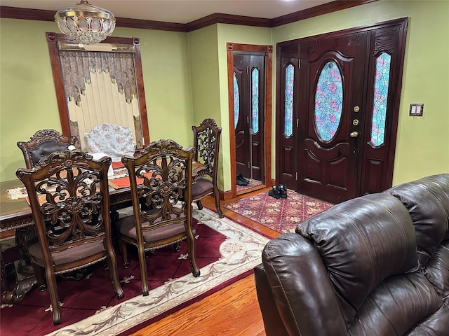 entryway with an inviting chandelier, ornamental molding, and wood finished floors