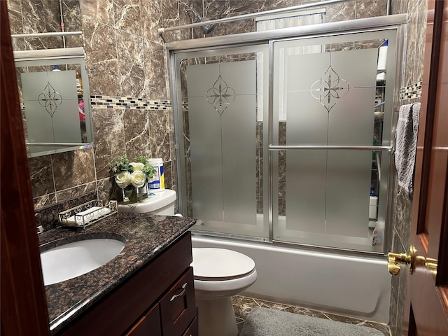 full bath with shower / bath combination with glass door, tile walls, backsplash, toilet, and vanity