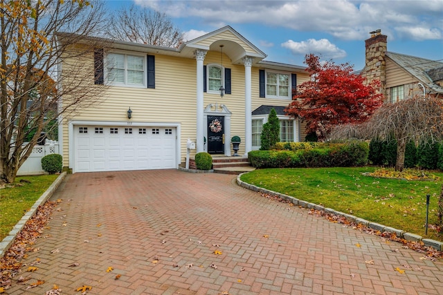 view of front facade with a garage, decorative driveway, and a front lawn