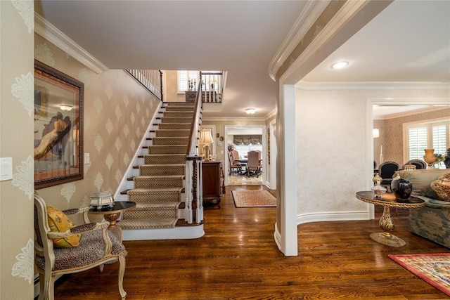 foyer entrance with wallpapered walls, crown molding, stairway, and wood finished floors