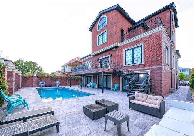 back of house featuring a fenced backyard, brick siding, an outdoor living space, stairs, and a patio area