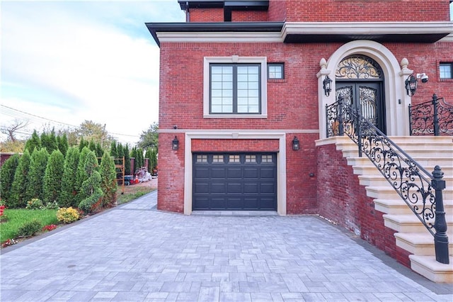 view of front of house featuring an attached garage, decorative driveway, and brick siding