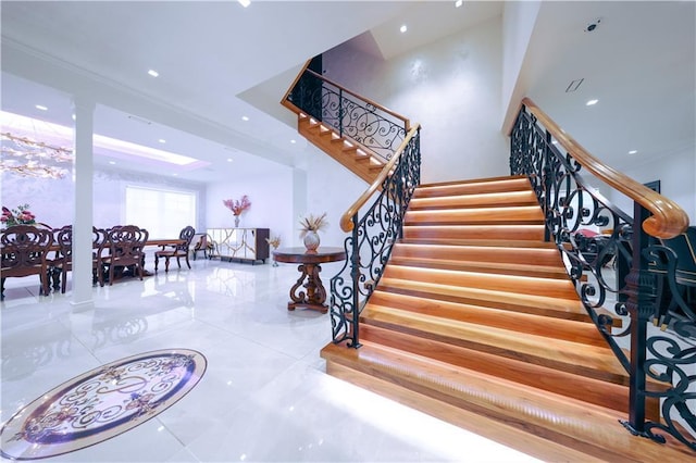 stairway with marble finish floor, a towering ceiling, and recessed lighting