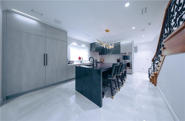 kitchen with a breakfast bar, modern cabinets, a sink, and a kitchen island with sink