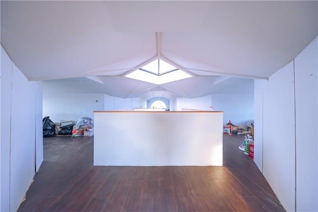 interior space featuring vaulted ceiling with skylight and wood finished floors