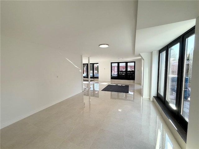 unfurnished living room featuring floor to ceiling windows and baseboards