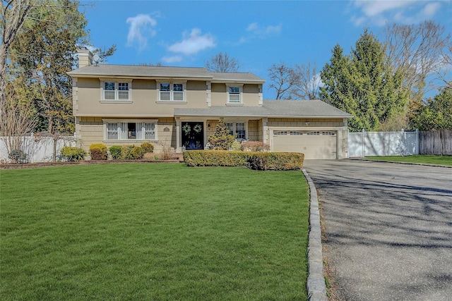 view of front of house featuring a front yard, an attached garage, fence, and driveway