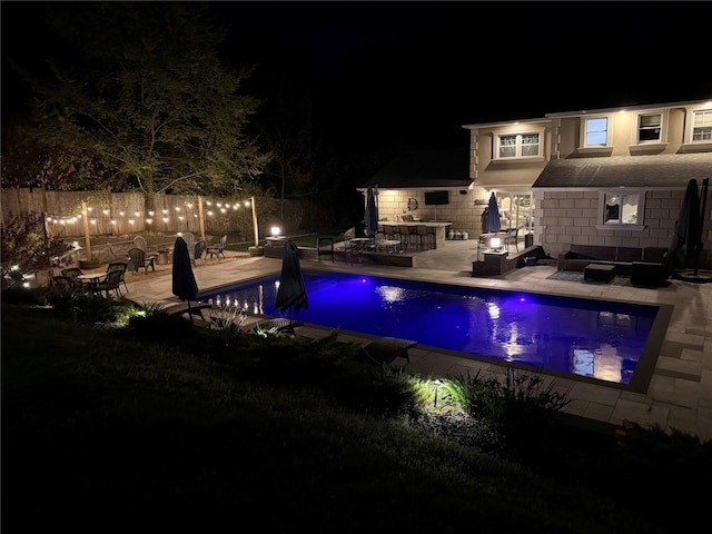 pool at twilight featuring an outdoor living space, a fenced in pool, and a patio