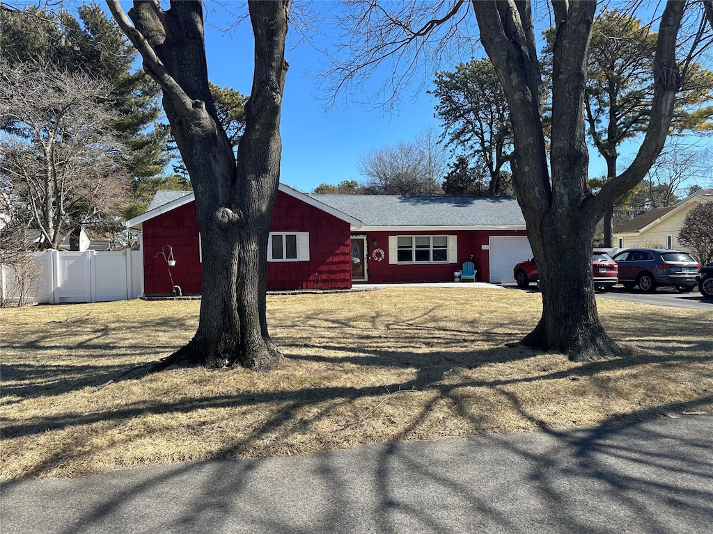 view of front of home featuring a garage, fence, and a front lawn