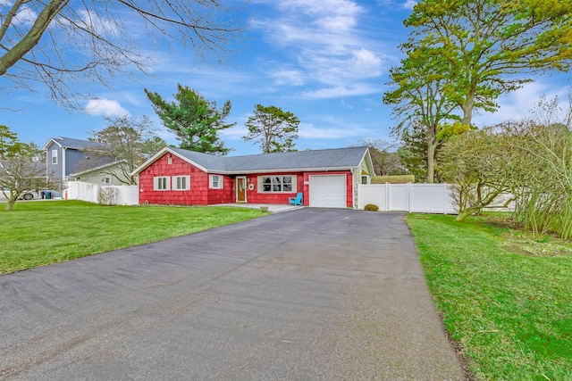 view of front of property with aphalt driveway, a front yard, fence, and an attached garage