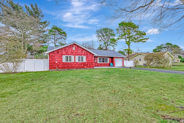 view of front facade featuring aphalt driveway, a front yard, fence, and an attached garage