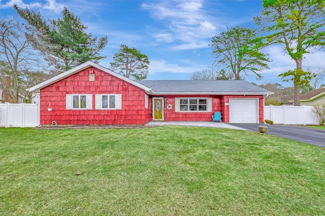 ranch-style home featuring an attached garage, fence, aphalt driveway, and a front yard