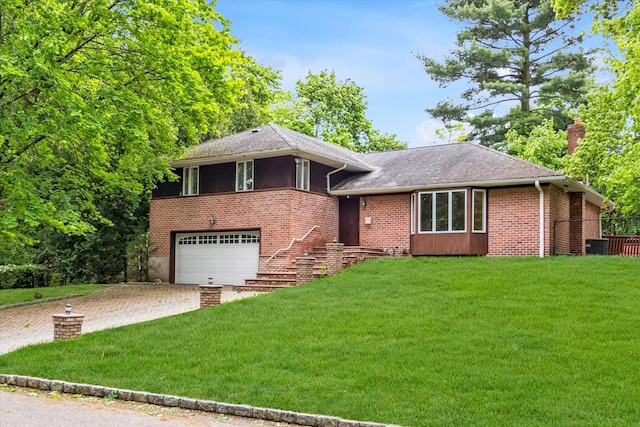 tri-level home with driveway, an attached garage, a front yard, and brick siding