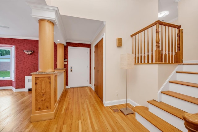 foyer entrance featuring ornamental molding, decorative columns, baseboards, and wallpapered walls