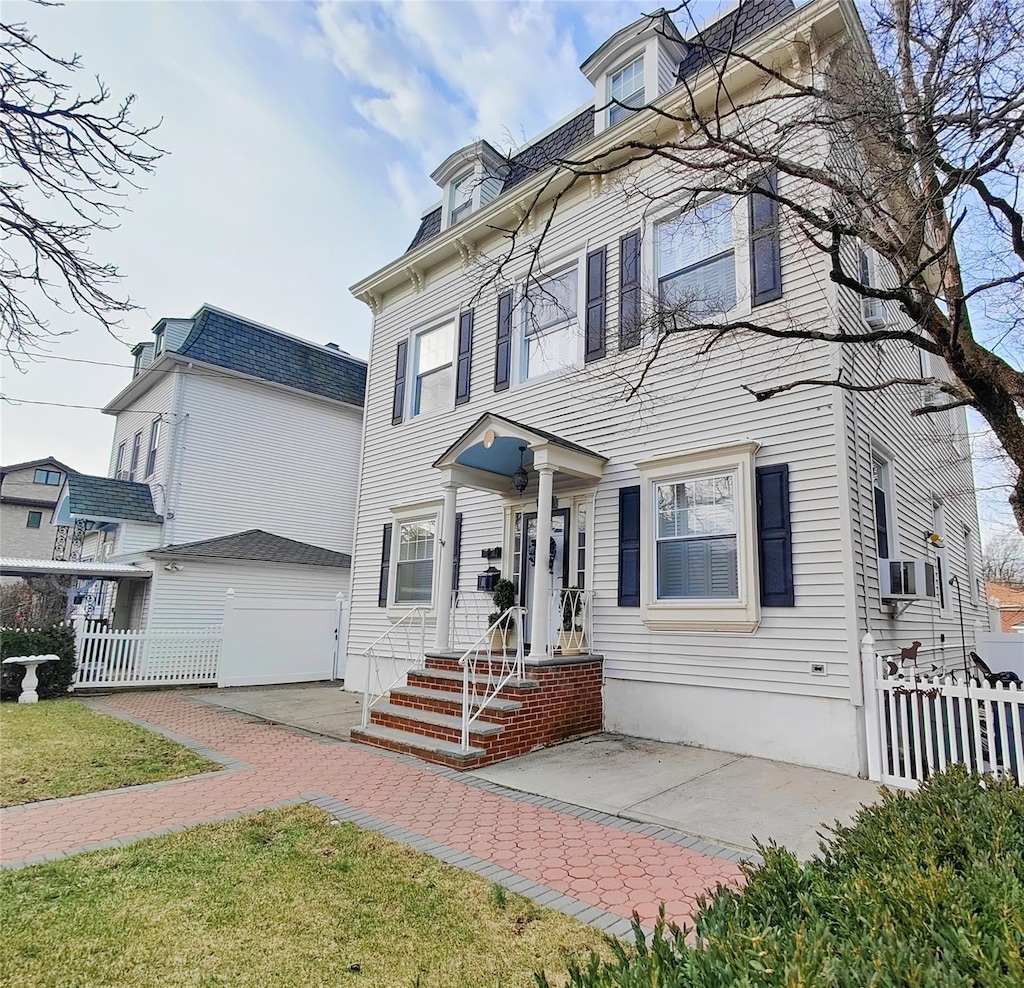 view of front of home featuring fence and mansard roof